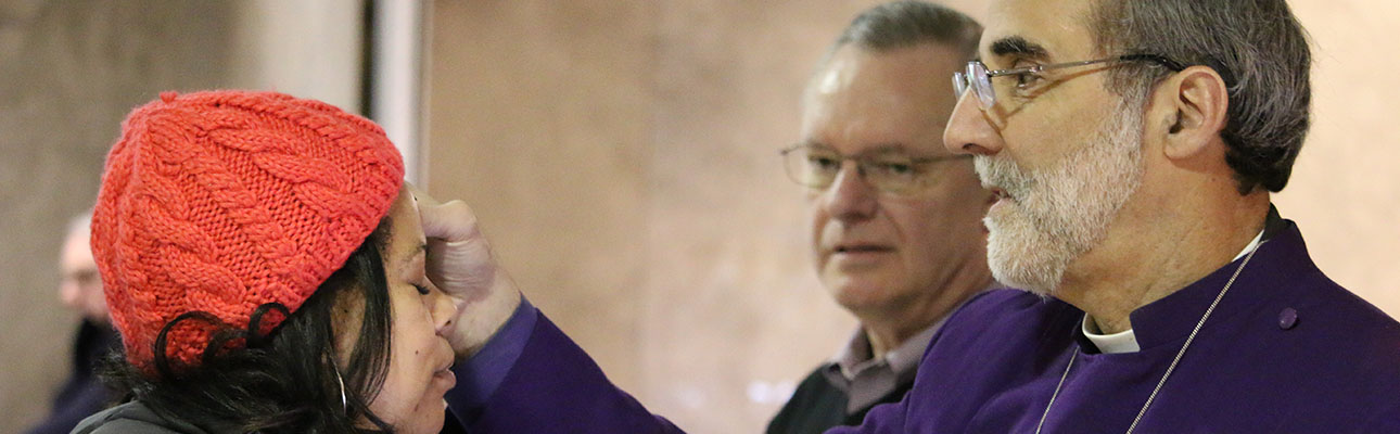 On Ash Wednesday 2015, Bishop Mark Beckwith gives "Ashes to Go" to a commuter at Newark Penn Station, assisted by diocesan staff member Paul Shackford. NINA NICHOLSON PHOTO