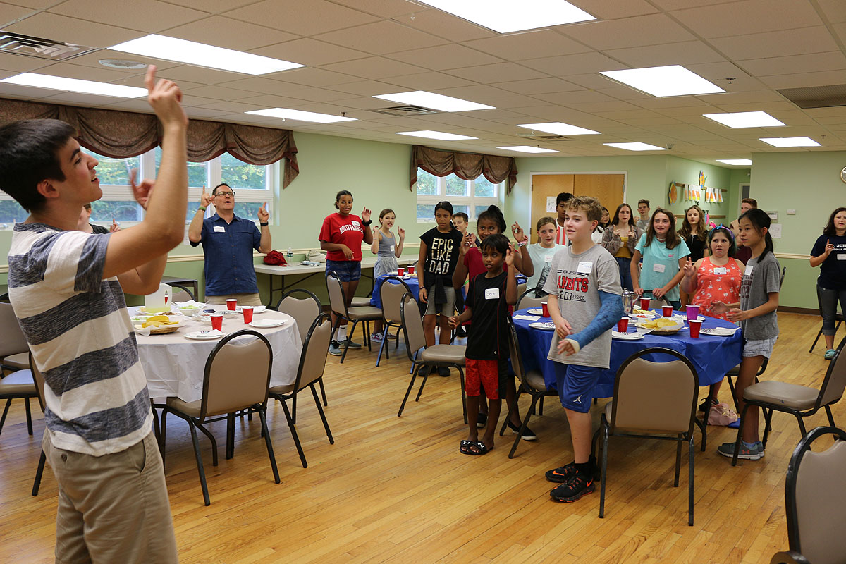 Youth Fellow Matt Porowski leads the group in singing the "Spiderman" grace.