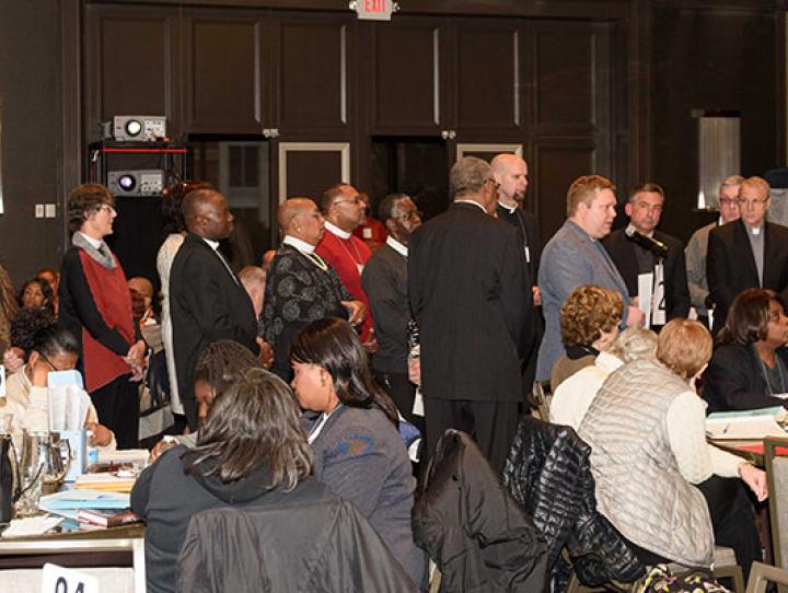 Surrounded by supporters, the Rev. J. Brent Bates (at microphone) reads his statement on the Sanctuary Church Movement and Immigrant Justice to Convention deputies. STEVEN BOSTON PHOTO