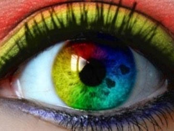 Close up of an opened eye with a rainbow colored contact lens.