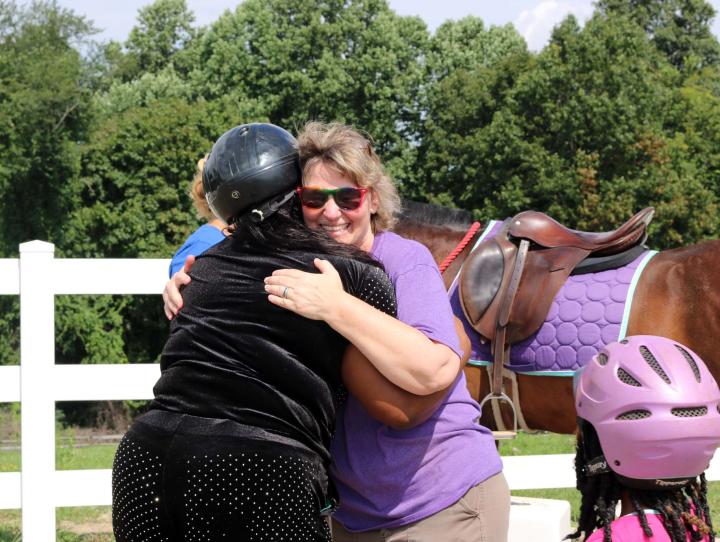 Colleen Wolfe, Program Director of Haven of Hope for Kids, hugs a mother after she and her children go horseback riding for the first time.