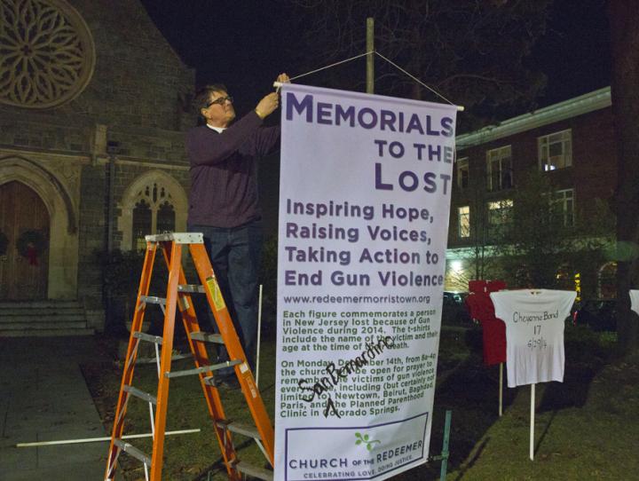 The Rev. Cynthia Black hangs a banner explaining Memorials to the Lost