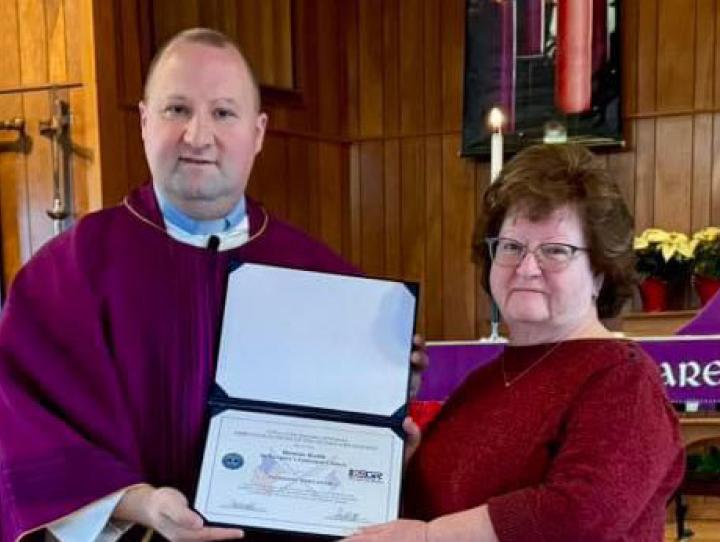 Fr. Aaron Oliver presents Bonnie Keith with a "Patriotic Employer" award on behalf of the Department of Defense.