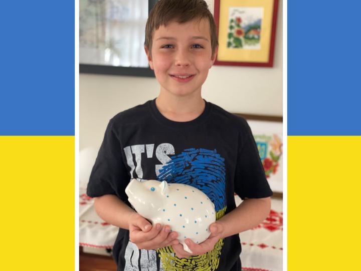 Lyubov Ferara's 10-year-old son with the piggy bank he emptied to contribute towards aid for Ukraine.