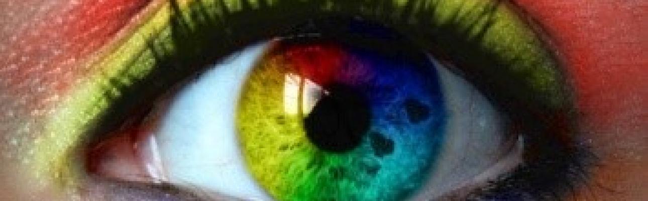 Close up of an opened eye with a rainbow colored contact lens.