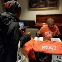 WASHINGTON: At 5:30 AM, Canon Greg Jacobs hands out T-shirts to bus riders at Episcopal House in Newark. NINA NICHOLSON PHOTO