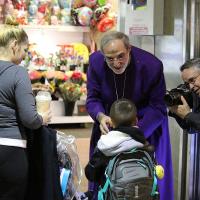 A Star-Ledger photographer photographs Bishop Mark Beckwith giving Ashes to Go to a family in Newark Penn Station. NINA NICHOLSON PHOTO