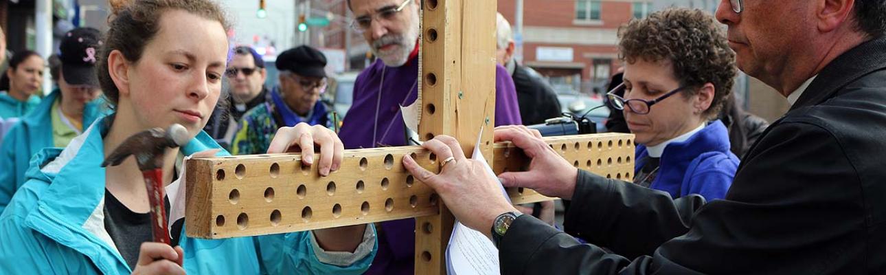 A worshipper hammers a nail into the cross at the first station