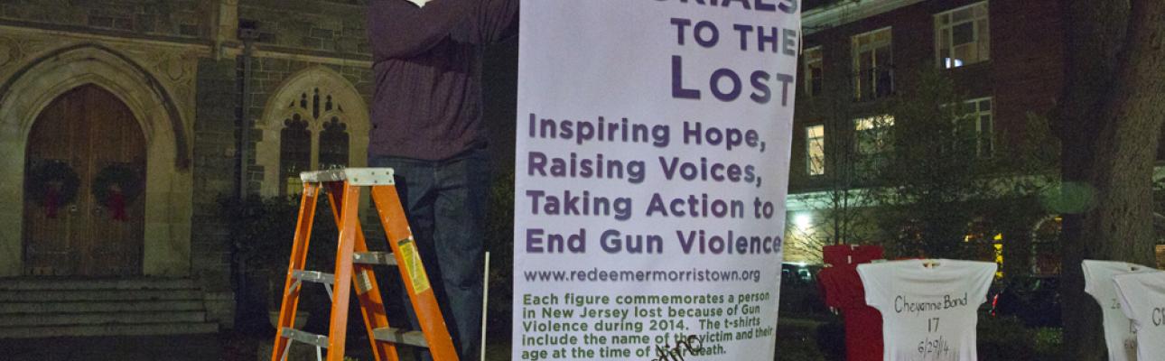 The Rev. Cynthia Black hangs a banner explaining Memorials to the Lost